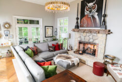 A cozy living room with a gray sectional sofa, fireplace, and large owl artwork above the mantel.