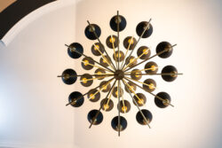 A modern, black and gold sputnik chandelier viewed from directly below against a white ceiling.